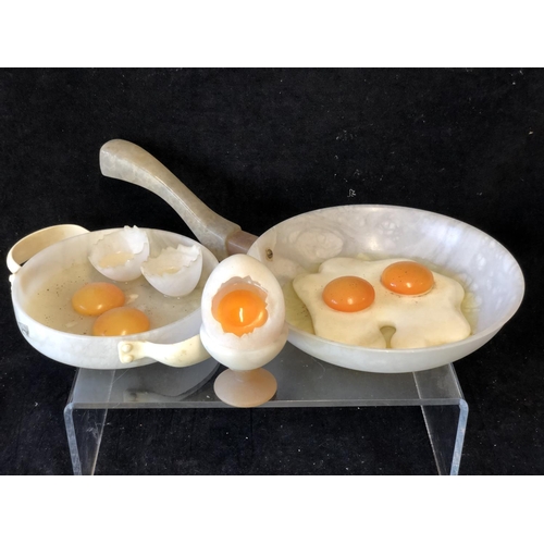 252 - Marco Ricciardi, Alabaster sculptures formed as fried eggs in av frying pan;  egg cup with cracked e... 