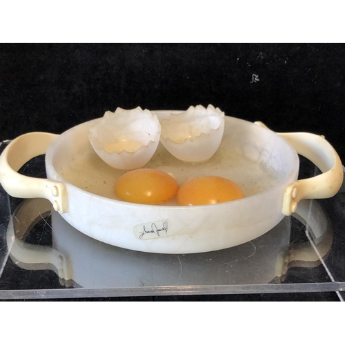 252 - Marco Ricciardi, Alabaster sculptures formed as fried eggs in av frying pan;  egg cup with cracked e... 