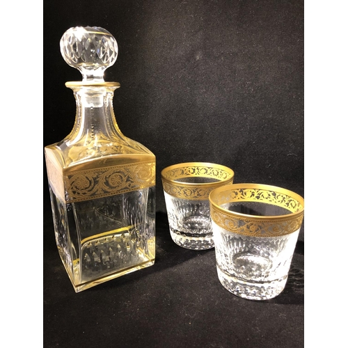 60 - Saint Louis - a Thistle Pattern decanter and stopper; and two tumblers, banded in gold with scrollin... 