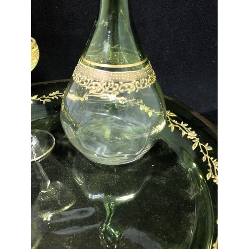 114 - Moser - a graduated green glass liquor set, comprising decanter and stopper and two glasses gilded w... 