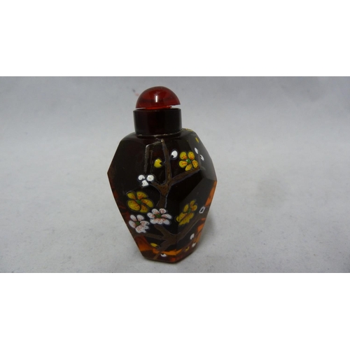 95 - Chinese Glass - a deep amber glass faceted snuff bottle enamelled in polychrome colours with prunus ... 