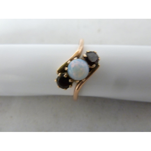 65 - A opal and garnet ring, set in rose coloured metal, unmarked, ring size K; and two opal set earrings... 