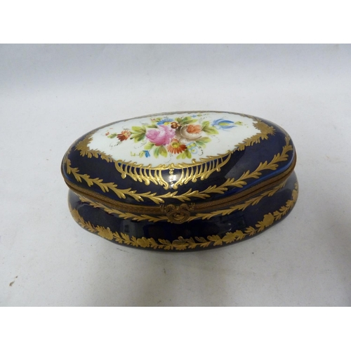 128 - A 'Sevres' porcelain box and cover, shaped oval, decorated with reserves of Summer flowers on a coba... 