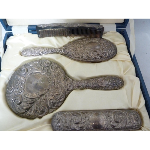 18 - A Victorian style silver mounted dressing table set in fitted cases, the backs repousse decorated wi... 