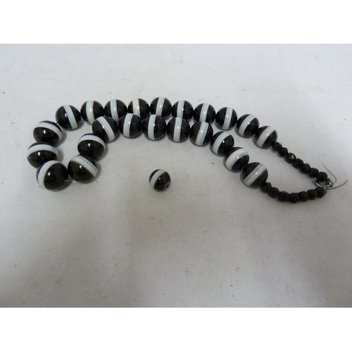 68 - A banded agate necklace, of 23 black and white globular beads, with evenly spaced stripe of white th... 