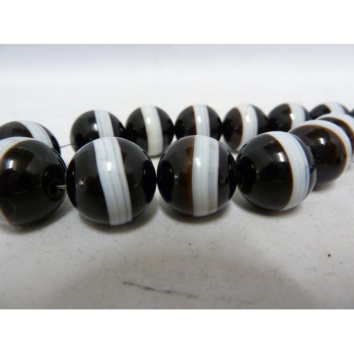 68 - A banded agate necklace, of 23 black and white globular beads, with evenly spaced stripe of white th... 