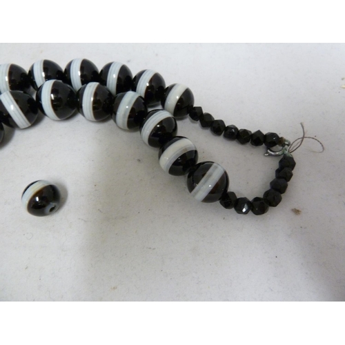 68 - A banded agate necklace, of 23 black and white globular beads, with evenly spaced stripe of white th... 