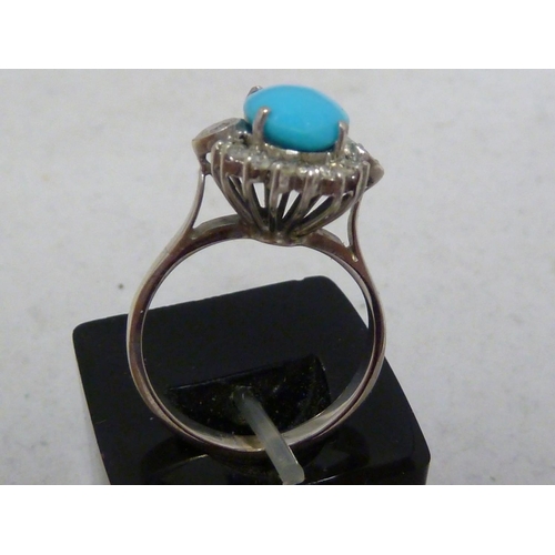 82 - A turquoise and diamond ring, the oval turquoise encircled by 18 round brilliant cut diamonds, set i... 