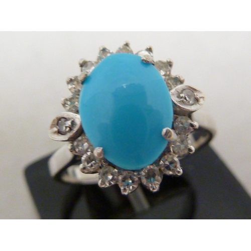 82 - A turquoise and diamond ring, the oval turquoise encircled by 18 round brilliant cut diamonds, set i... 