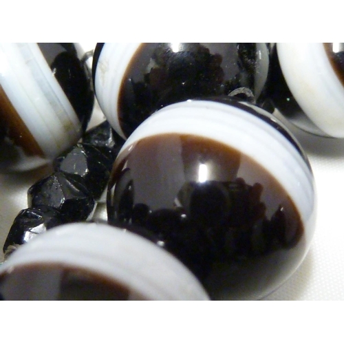 68 - A banded agate necklace, of 23 black and white globular beads, with evenly spaced stripe of white th... 