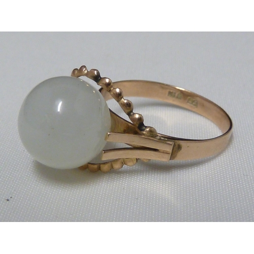 70 - A Chinese white jade ring, the ball form stone set in wirework and on a yellow metal shank stamped K... 