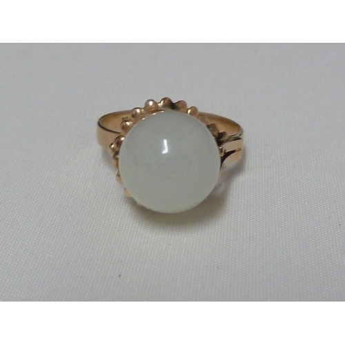 70 - A Chinese white jade ring, the ball form stone set in wirework and on a yellow metal shank stamped K... 