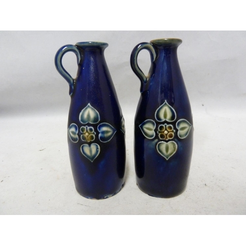 103 - A pair of Royal Doulton stoneware miniature jugs, each with high placed strap handle and decorated w... 