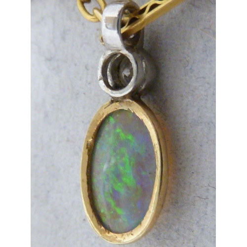 44 - An opal and diamond pendant, the oval opal set in yellow metal, surmounted by a single round brillia... 