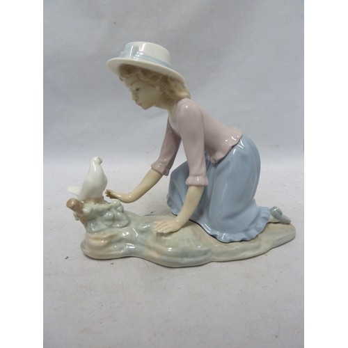 243 - Nao - a porcelain figure of a girl kneeling with a dove on a tree stump, 16.5cm high approx