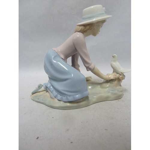 243 - Nao - a porcelain figure of a girl kneeling with a dove on a tree stump, 16.5cm high approx