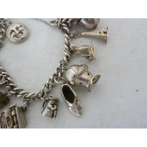 12 - A silver charm bracelet with heart form fastening, comprising piskie, full moon, donald Duck, 1/2 fr... 