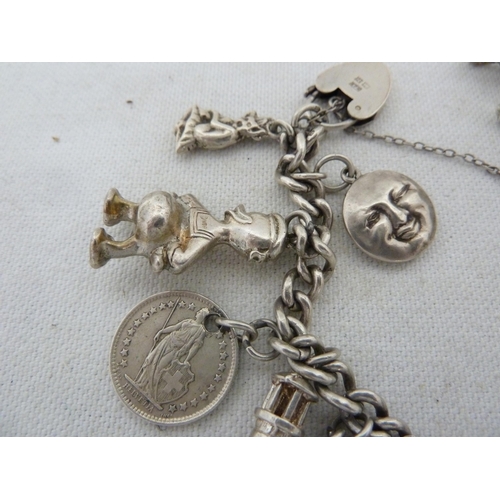 12 - A silver charm bracelet with heart form fastening, comprising piskie, full moon, donald Duck, 1/2 fr... 