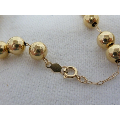 16 - A yellow metal hollow bead necklace, each bead suspended on a yellow metal chain running through all... 