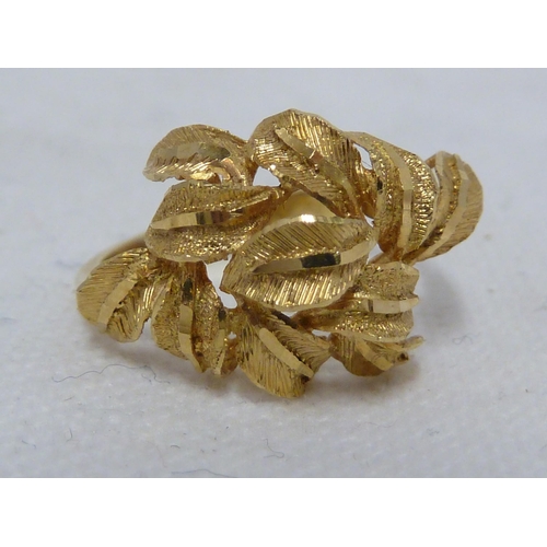 38 - A yellow metal ring, tooled with leaf motifs in high relief, ring size N 1/2, 2.8grms