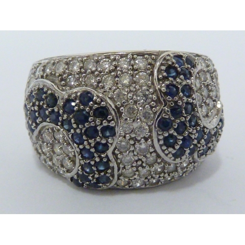 60 - a Diamond and sapphire ring, the pave ground of close pack round diamonds with a design of stylised ... 