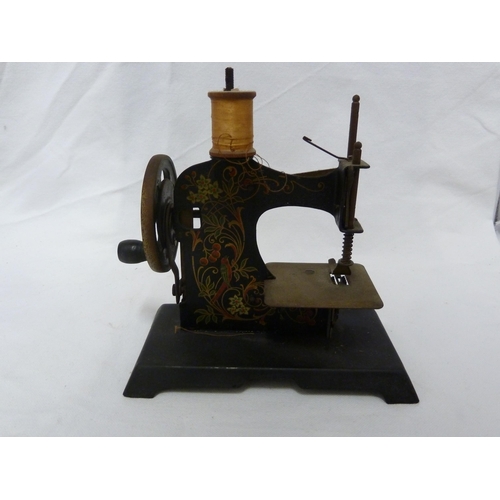 121 - A miniature sewing machine, with elaborate decoration of scrolling fronds, 16cm max