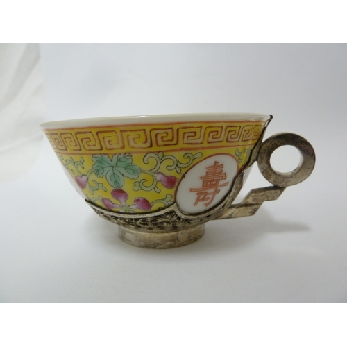 149 - A Chinese porcelain white metal mounted cup and saucer, the porcelain teabowl decorated with good fo... 