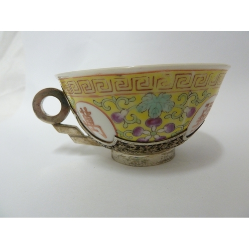 149 - A Chinese porcelain white metal mounted cup and saucer, the porcelain teabowl decorated with good fo... 