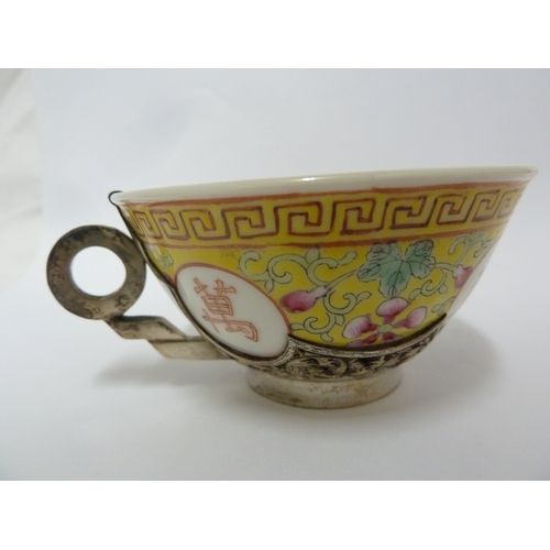 78 - A Chinese porcelain white metal mounted cup and saucer, the porcelain teabowl decorated with good fo... 