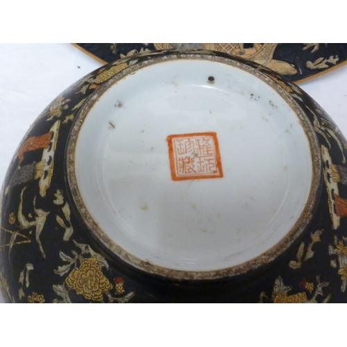 61 - A Chinese porcelain punch bowl; and a charger similar, each decorated with figures on a famille noir... 