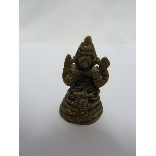 147 - A Balinese lion dog carving; and a small cast brass figure of Ganesh, 10cm high (2)