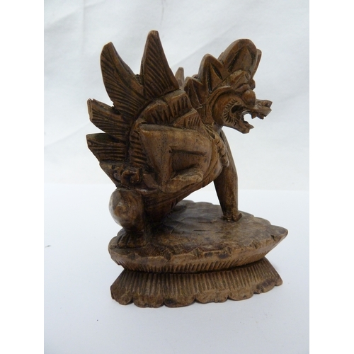 147 - A Balinese lion dog carving; and a small cast brass figure of Ganesh, 10cm high (2)