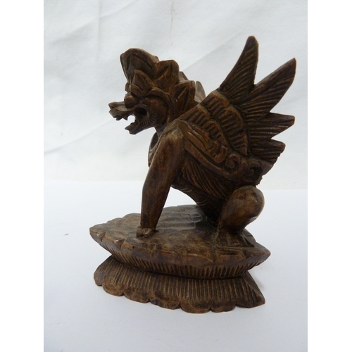 147 - A Balinese lion dog carving; and a small cast brass figure of Ganesh, 10cm high (2)