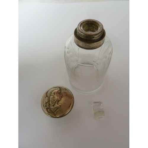 107 - A WMF toilet water bottle, the metal cover decorated with a maidens head with flowing tresses over a... 