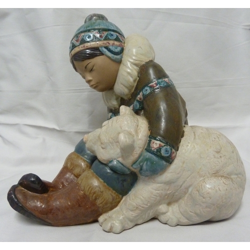 57 - A large size Lladro figure of a Inuit boy and polar bear, he seated holding the bear under one arm, ... 