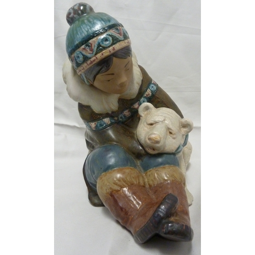 57 - A large size Lladro figure of a Inuit boy and polar bear, he seated holding the bear under one arm, ... 