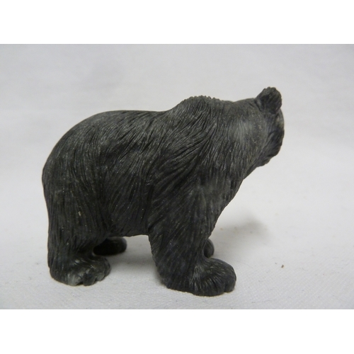 44 - A carved coal figure of a bear, with applied glass eyes, 9 cm max.