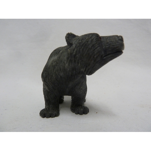 44 - A carved coal figure of a bear, with applied glass eyes, 9 cm max.