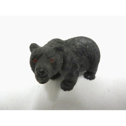 44 - A carved coal figure of a bear, with applied glass eyes, 9 cm max.