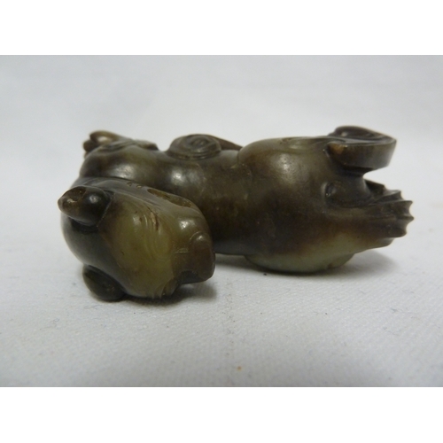 41 - A Chinese olive green jade Kylin, modelled crouching with head turned backwards, 7.5cm max; and a wo... 