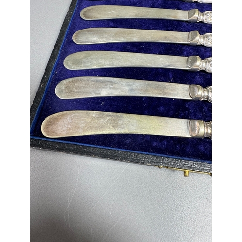 35 - Cased set of six ornate silver‑handled table knives, fitted case — 149g.

Heavily embossed silver ha... 