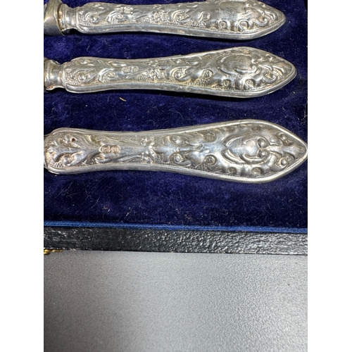 35 - Cased set of six ornate silver‑handled table knives, fitted case — 149g.

Heavily embossed silver ha... 