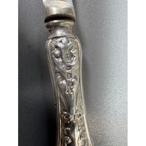 35 - Cased set of six ornate silver‑handled table knives, fitted case — 149g.

Heavily embossed silver ha... 