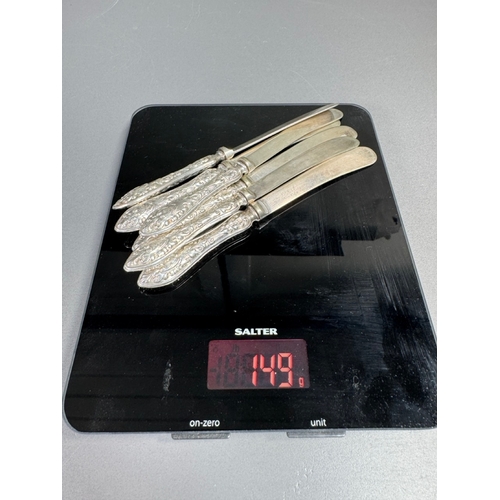 35 - Cased set of six ornate silver‑handled table knives, fitted case — 149g.

Heavily embossed silver ha... 
