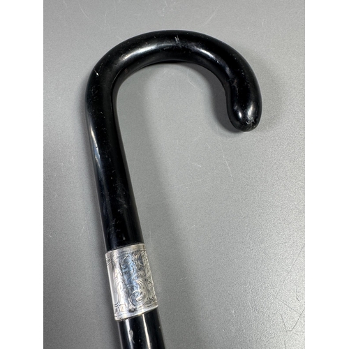 28 - Ebonised walking cane with engraved silver collar & cap, brass ferrule — approx. 95cm.

Ebonised can... 