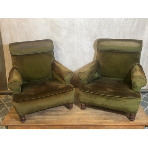 A Pair of Howard Style Deep Seated Club Chairs in Olive Green Velvet

A pair of Howard style easy chairs, United Kingdom, mid-20th century. The set includes:

The first easy chair is upholstered in an olive green plush velvet and features a deep, sprung seat with low, wide scrolled arms. The chair is designed with a prominent rolled backrest and is supported by turned wooden front legs with multiple ring mouldings. The rear support is provided by splayed, square-section wooden legs. No maker's marks, stamps, or labels are visible on the legs or exterior surfaces.

The second easy chair matches the first in all aspects of design and construction, featuring identical proportions and scrolled armrests. It is similarly upholstered in olive green velvet and sits upon matching turned wooden front feet and splayed rear legs. The chair exhibits a classic country house silhouette and retains its internal padding and springing.