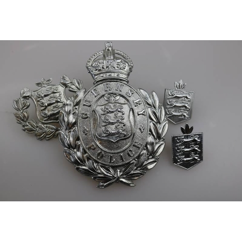 195 - An obsolete Guernsey Police helmet badge together with obsolete Guernsey Police cap badge and two co... 