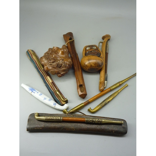 186 - A selection of oriental pipes together with hand carved grotesque tobacco pouches and pipe.