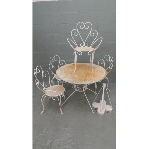 704 - A metal garden table and four chairs with an added parasol base. Thne table measures approx' 99cm di... 