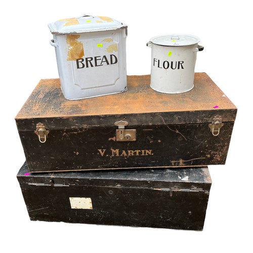 2 - Two empty black metal trunks together with enamel kitchen ware.